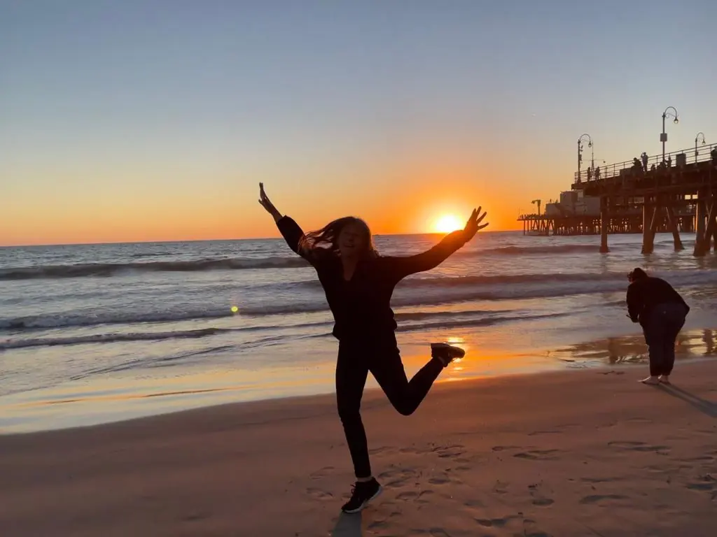 Carla Giúdice saltando en una playa al atardecer
